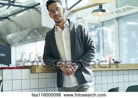 Stock Photo - Smiling businessman standing in restaurant. Fotosearch