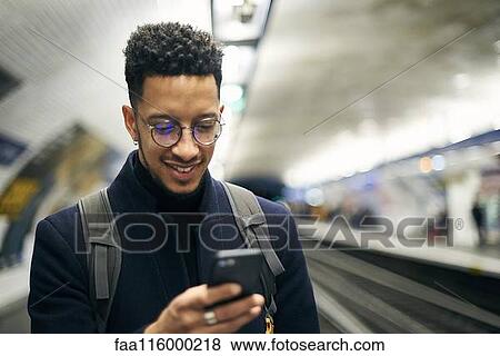 Stock Photo - Smiling businessman using smartphone. Fotosearch