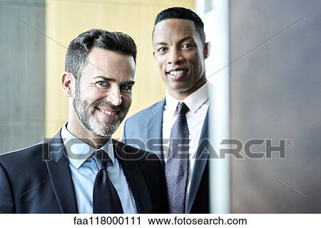 Stock Image - Smiling businessmen standing in hotel lobby. Fotosearch