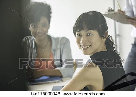 Smiling businesswomen sitting in office View Large Photo Image Stock Photo - Smiling businesswomen sitting in office. Fotosearch
