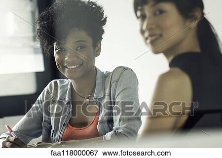 Smiling businesswomen sitting in office View Large Photo Image Stock Photo - Smiling businesswomen sitting in office. Fotosearch