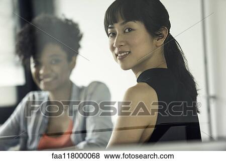 Stock Photo - Smiling businesswomen sitting in office. Fotosearch