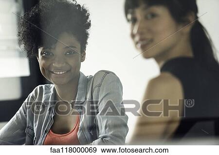 Smiling businesswomen sitting in office View Large Photo Image Stock Photo - Smiling businesswomen sitting in office. Fotosearch