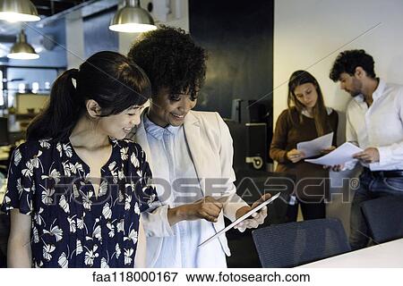 Smiling businesswomen using digital tablet in office View Large Photo Image Stock Photo - Smiling businesswomen using digital tablet in office. Fotosearch