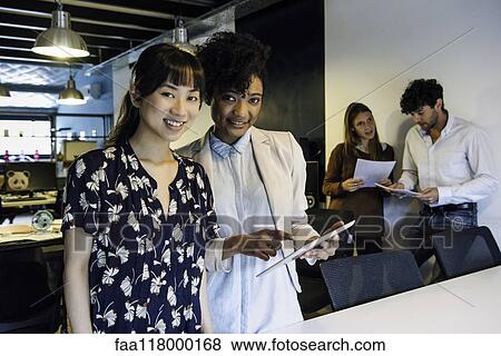 Smiling businesswomen using digital tablet in office View Large Photo Image Stock Photo - Smiling businesswomen using digital tablet in office. Fotosearch