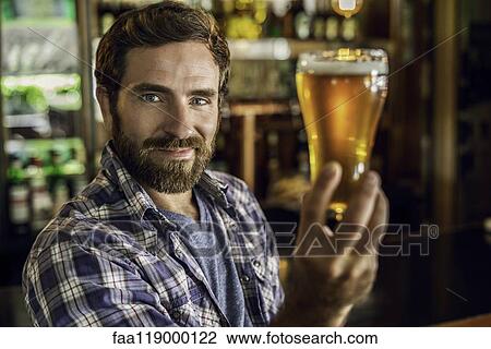 Stock Image - Smiling man holding a beer glass. Fotosearch