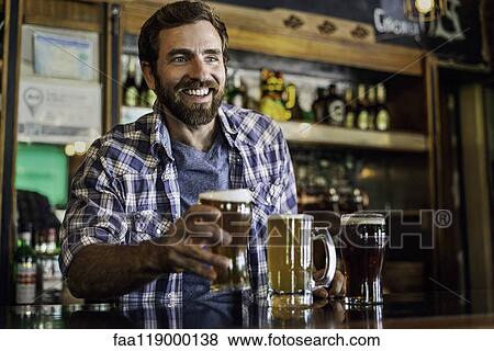 Smiling man serving beer View Large Photo Image Stock Photo - Smiling man serving beer. Fotosearch