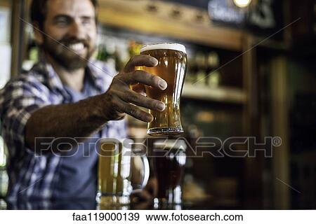 Smiling man serving beer View Large Photo Image Stock Photo - Smiling man serving beer. Fotosearch