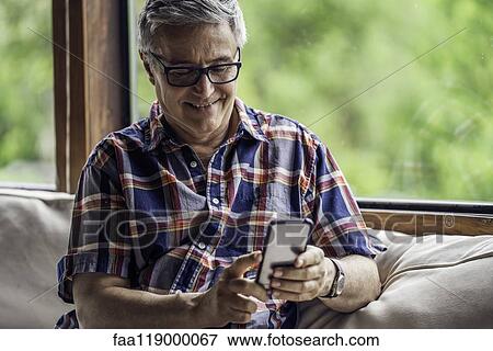Smiling mature man using smartphone View Large Photo Image Stock Photo - Smiling mature man using smartphone. Fotosearch