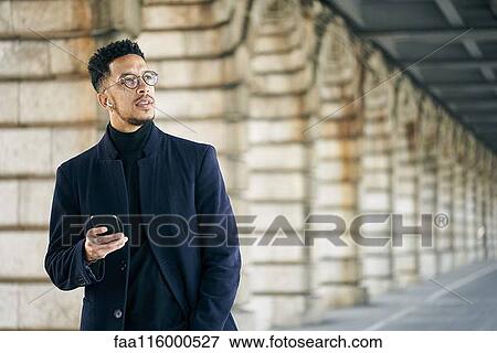 Thoughtful businessman holding smartphone View Large Photo Image Stock Photo - Thoughtful businessman holding smartphone. Fotosearch