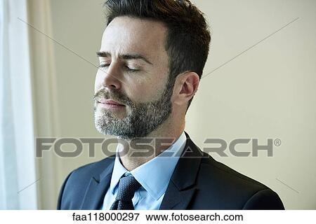 Thoughtful businessman standing in hotel View Large Photo Image Stock Photo - Thoughtful businessman standing in hotel. Fotosearch