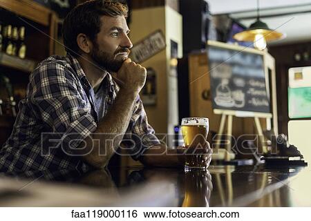 Thoughtful man holding glass of beer View Large Photo Image Stock Photograph - Thoughtful man holding glass of beer. Fotosearch