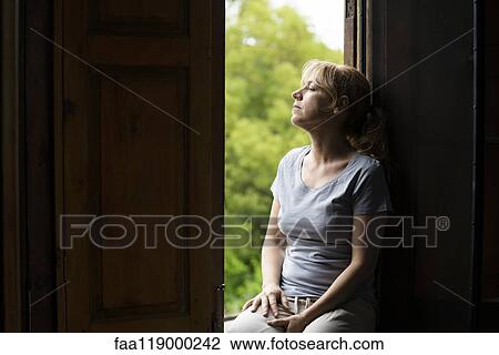 Thoughtful woman sitting on window View Large Photo Image Stock Image - Thoughtful woman sitting on window. Fotosearch