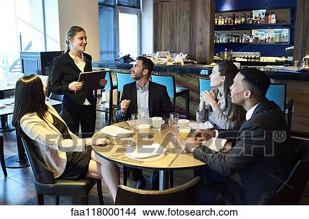 Picture - Waitress taking orders from business people in bar. Fotosearch