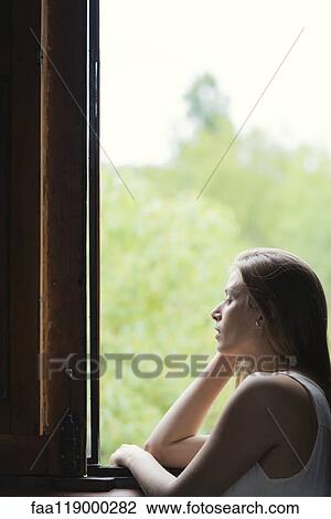 Stock Image - Woman looking through window. Fotosearch