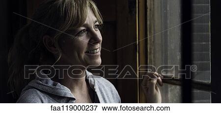 Woman looking through window View Large Photo Image Stock Photo - Woman looking through window. Fotosearch