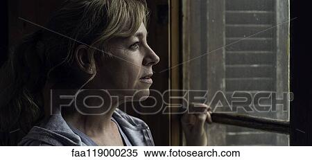Stock Photography - Woman looking through window. Fotosearch