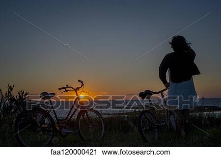 Woman standing by bicycles View Large Photo Image Stock Image - Woman standing by bicycles. Fotosearch