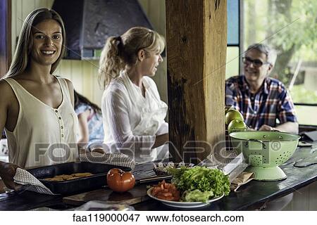 Stock Photo - Woman with her parents standing in kitchen. Fotosearch