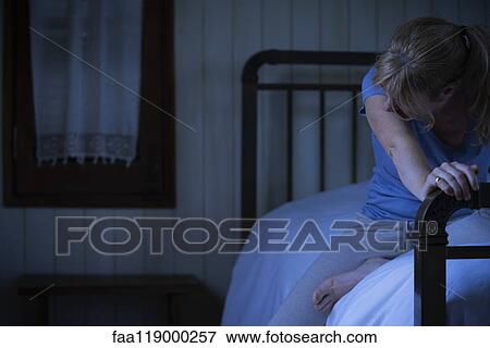 Worried woman sitting on bed View Large Photo Image Stock Photo - Worried woman sitting on bed. Fotosearch