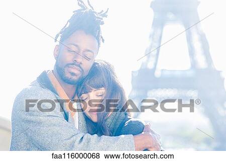 Stock Photo - Young couple embracing in front of Eiffel Tower. Fotosearch