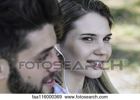 Stock Photo - Young couple listening music on headphones. Fotosearch