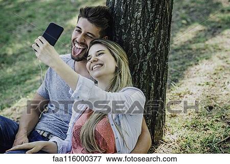 Young couple listening to music and taking selfie with a smartphone View Large Photo Image Stock Photo - Young couple listening to music and taking selfie with a smartphone. Fotosearch