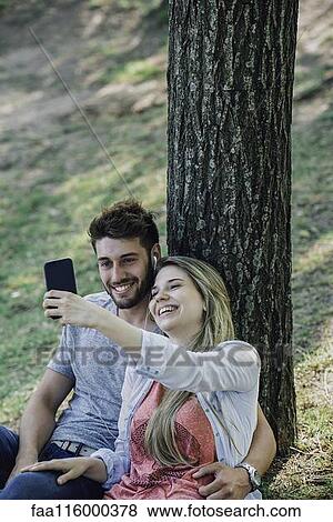 Young couple listening to music and taking selfie with a smartphone View Large Photo Image Stock Photo - Young couple listening to music and taking selfie with a smartphone. Fotosearch