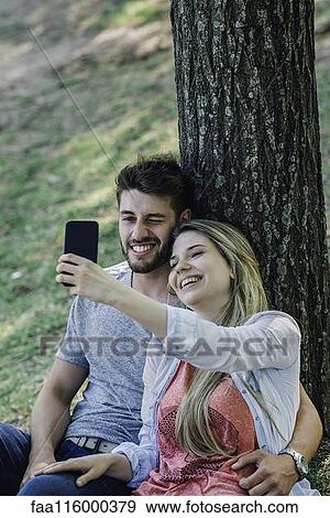 Young couple listening to music and taking selfie with a smartphone View Large Photo Image Stock Photo - Young couple listening to music and taking selfie with a smartphone. Fotosearch