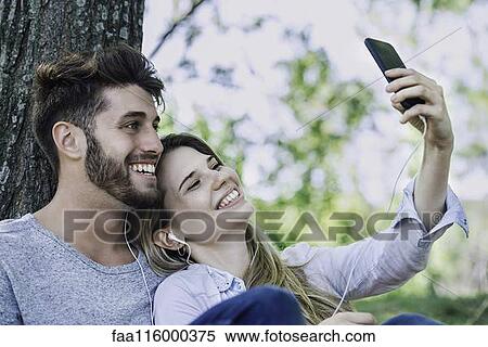 Young couple listening to music and taking selfie with a smartphone View Large Photo Image Stock Photography - Young couple listening to music and taking selfie with a smartphone. Fotosearch