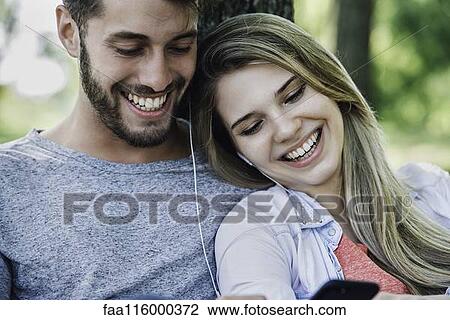 Young couple listening to music on smartphone View Large Photo Image Stock Image - Young couple listening to music on smartphone. Fotosearch