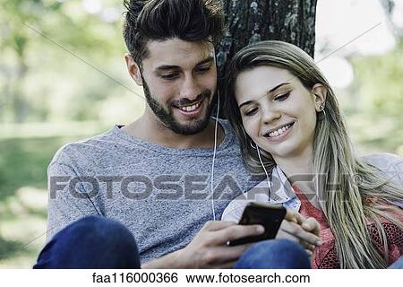 Young couple listening to music on smartphone View Large Photo Image Stock Photograph - Young couple listening to music on smartphone. Fotosearch