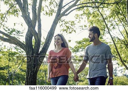Young couple walking in park View Large Photo Image Stock Photo - Young couple walking in park. Fotosearch