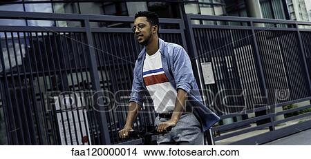 Young man riding push scooter View Large Photo Image Picture - Young man riding push scooter. Fotosearch