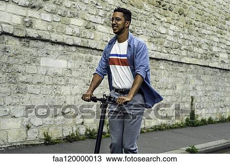 Young man riding push scooter View Large Photo Image Stock Image - Young man riding push scooter. Fotosearch