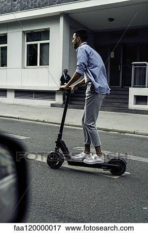 Young man riding push scooter View Large Photo Image Stock Photo - Young man riding push scooter. Fotosearch