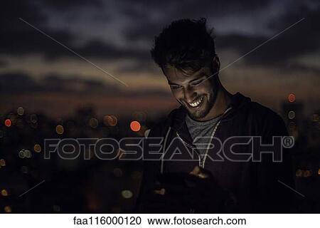 Stock Image - Young man using smartphone. Fotosearch