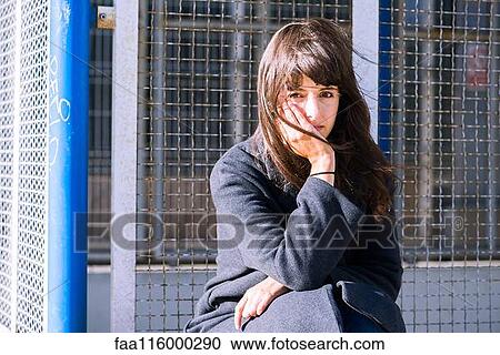 Young woman sitting near fence View Large Photo Image Stock Image - Young woman sitting near fence. Fotosearch