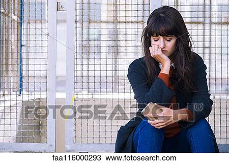 Young woman sitting near fence View Large Photo Image Stock Image - Young woman sitting near fence. Fotosearch