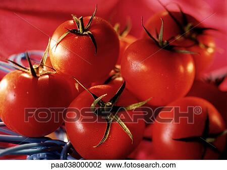 Stock Image - Pile of red tomatoes with green stems, close-up. Fotosearch
