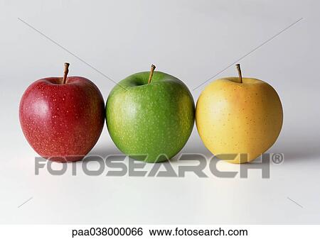 Stock Photograph - Three apples in a row, red, green, yellow, close-up. Fotosearch