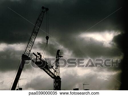 Stock Photography - Cranes under stormy sky, low angle view. Fotosearch