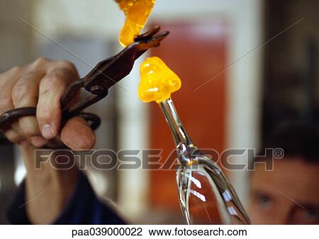 Stock Image - Hand holding scissors, cutting molten glass. Fotosearch
