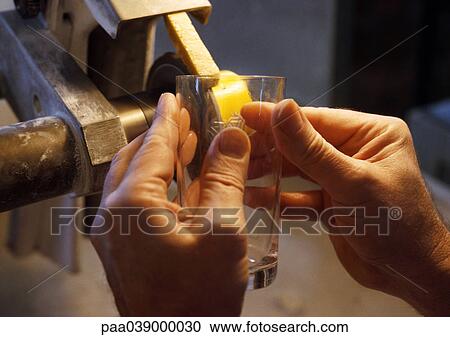 Stock Image - Hands holding glass to be engraved, close-up. Fotosearch