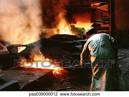 Stock Image - Man bending forward, working in blast furnace, rear view. Fotosearch