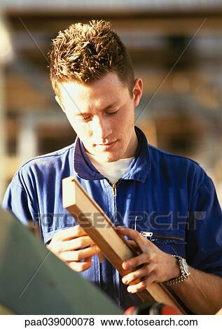 Man in coveralls, holding plank View Large Photo Image Stock Photo - Man in coveralls, holding plank. Fotosearch