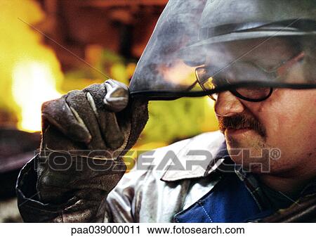 Stock Image - Man wearing protective mask, holding eyeshade. Fotosearch
