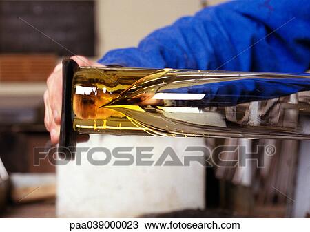 Stock Image - Man working molten glass, focus on hands. Fotosearch