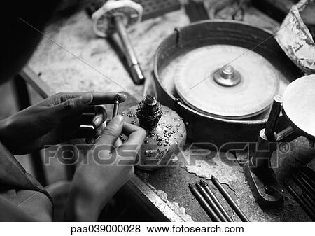 Stock Photo - Person standing in front of workbench, focus on hands, b&w. Fotosearch