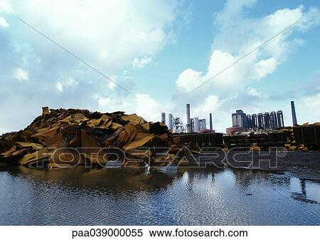 Stock Photography - Scrap iron at edge of water, power plants in background. Fotosearch